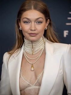 a woman in a white suit with pearls on her neck