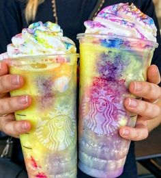 two people holding up colorful drinks in their hands