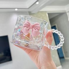 a person holding up a clear square shaped object with a pink bow on it