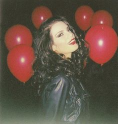 a woman standing in front of red balloons