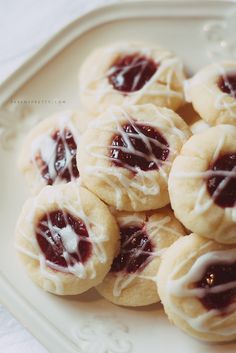 small cookies with white icing and raspberry toppings on a plate, ready to be eaten