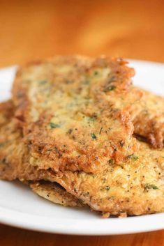 two crab cakes on a white plate sitting on a wooden table