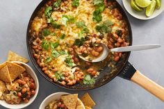 a skillet filled with beans, tortilla chips and guacamole