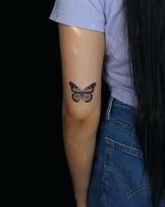 a woman's arm with a butterfly tattoo on the back of her left arm