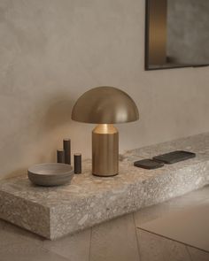 a lamp sitting on top of a table next to a bowl and other items in front of a mirror