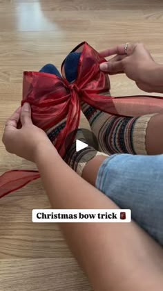 a person tying a bow on top of a pair of shoes that are sitting on the floor