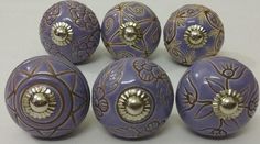 six purple and gold decorated knobs on white surface