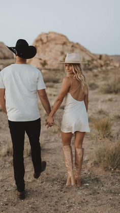 a man and woman walking in the desert holding hands