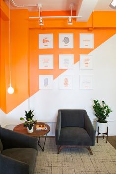 an office with orange and white walls, two chairs and a coffee table in the middle