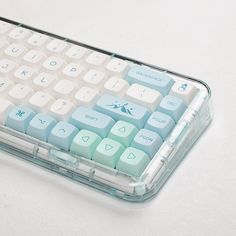 a clear plastic case with blue and green keys on the bottom, sitting on a white surface