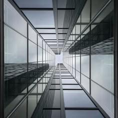 an upward view of some very tall buildings with windows on each side and sky in the background