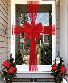 two potted plants with red ribbons on the front door