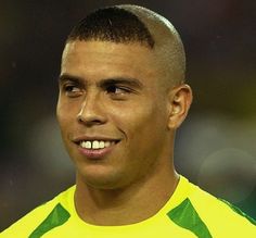 a close up of a soccer player wearing a yellow shirt and smiling at the camera