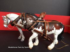 a toy horse with saddle and bridle on it's back standing next to a red wall