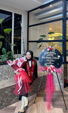 a woman standing next to a sign holding flowers