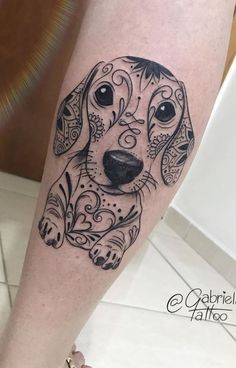 a black and white dog tattoo on the right leg, with an ornate design around it