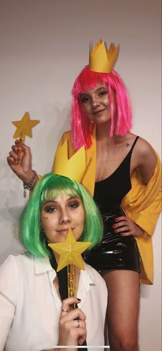 two women dressed in costumes and wigs holding star wands with stars on them