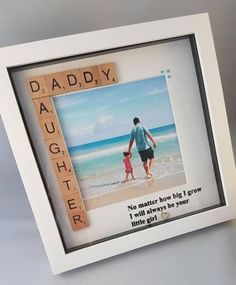 a father and daughter holding hands on the beach with scrabbles in front of them