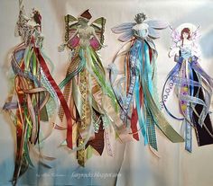 three paper dolls are hanging on the wall with ribbons attached to it's sides