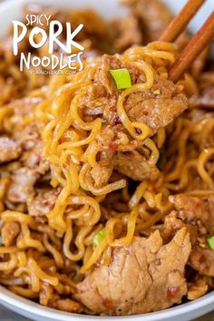 a bowl filled with meat and noodles on top of a wooden table next to chopsticks