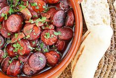 a bowl filled with cooked sausage next to bread