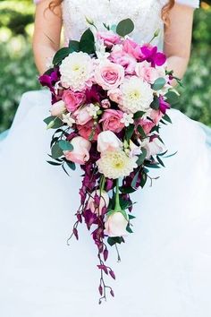 a bride holding a bouquet of pink and white flowers