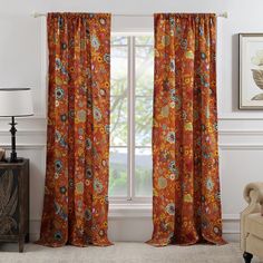 an orange floral curtain hanging in front of a window with white walls and windowsill