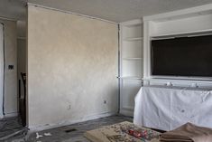 a living room that is being remodeled with white paint on the walls and carpeted floor