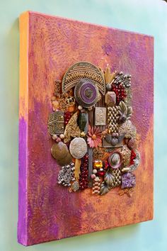 an art piece is hanging on the wall with beads and other things around it,