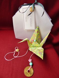 an origami bird next to a coin on a red cloth with a tag