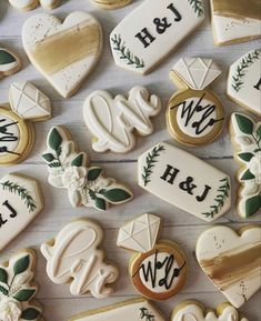 decorated cookies are arranged on a table with white and gold accents, including monogrammed letters