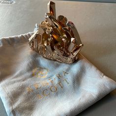 a gold ring sitting on top of a white cloth next to a napkin with the word regal scott written on it