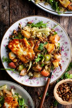 two plates filled with chicken and vegetables on top of a wooden table next to a bowl of beans