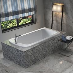 a bath tub sitting next to a window in a room with tile floors and walls