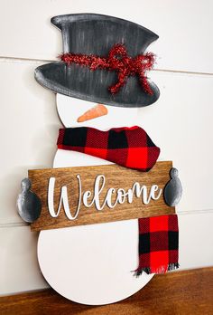 a wooden sign that says welcome with a snowman's hat and scarf