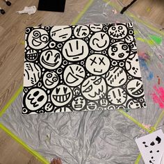 someone is painting on the floor with black and white designs in front of them,