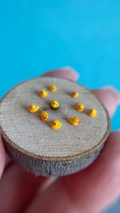 small yellow rubber ducks sitting on top of a piece of wood in someone's hand