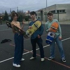 three young men holding skateboards in an empty parking lot