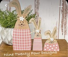 two wooden rabbits sitting on top of a table next to a potted green plant