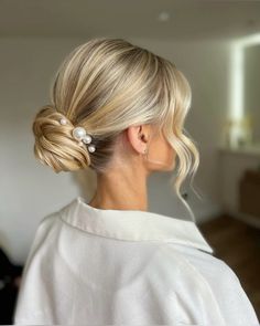 a woman with blonde hair wearing a white sweater and pearled clip in her hair