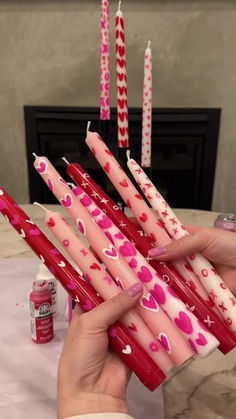 pink candles with hearts on them are being held by someone's hand over a table