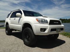 a white toyota truck is parked by the water