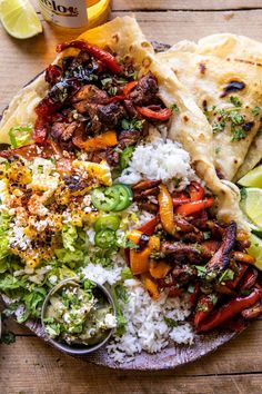 a plate full of mexican food with rice, meat and veggies on it