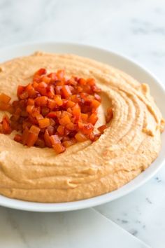 a white plate topped with hummus and chopped carrots