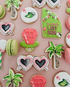 many decorated cookies on a pink surface with palm trees and other items in the background