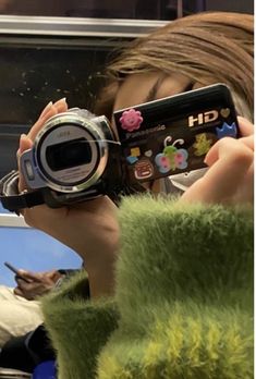 a woman holding up a camera to take a picture with her cell phone in front of her face