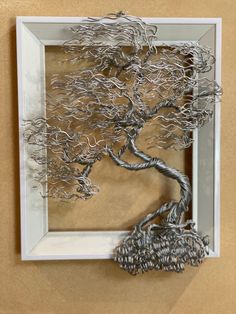 a metal tree sculpture in a white frame