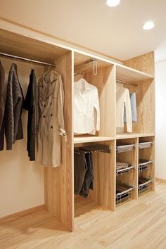 an organized closet with clothes and jackets hanging on the wall, along with wooden flooring