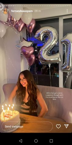 a woman sitting at a table in front of a birthday cake with candles on it