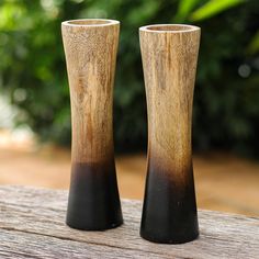 two black and brown vases sitting on top of a wooden table next to each other